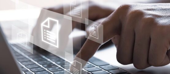 A person using a laptop keyboard with digital document icons hovering above, suggesting file management or data access.